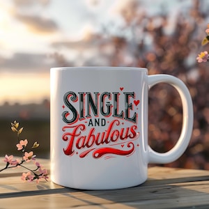 May include: White ceramic mug with the words "SINGLE and Fabulous" in a decorative, red and green font. The mug has a curved handle and is set against a blurred background of a sunset and foliage.