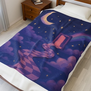 May include: A blue blanket with a whimsical night sky design. The blanket features a crescent moon, stars, and clouds in shades of purple and blue. A checkered path leads from a framed portal, with a rainbow and a dreamy aesthetic.