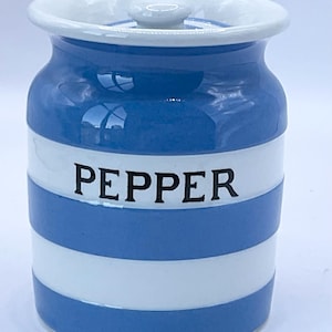 May include: A ceramic pepper jar with a lid. The jar is cylindrical with alternating horizontal stripes of blue and white. The word "PEPPER" is printed in black on the white stripe. The lid and rim are white.