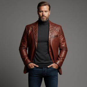 May include: A brown leather blazer with diamond-stitched shoulder and upper chest panels. The blazer is worn over a dark gray turtleneck sweater and paired with blue jeans. The model has a beard and is standing in front of a gray background.