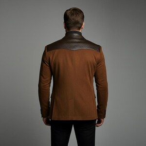 May include: A brown blazer with a textured, dark brown leather shoulder yoke. The blazer has a classic design with a two-button closure and a notched lapel. The model is wearing black pants.