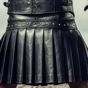 May include: A black leather kilt with pleated design. The kilt features a studded belt and is part of a leather outfit. The image shows a close-up of the kilt and the upper part of the outfit, suggesting a focus on alternative fashion or cosplay.