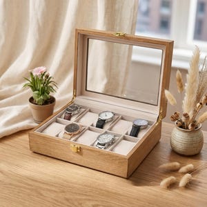 Puede incluir: Una caja de madera para relojes con tapa de cristal, que muestra ocho relojes con correas de varios colores. La caja está abierta, revelando los relojes sobre cojines color crema. La madera tiene una veta natural, y la caja está sobre una superficie de madera.