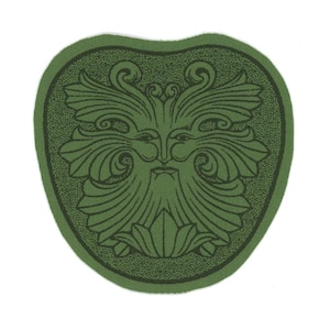 May include: A green patch featuring a stylized Green Man face with a beard and leafy details. The design is in a darker green, set against a lighter green background with a dotted border. The patch has a heart-like shape.