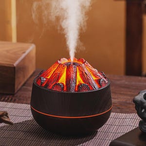 May include: A volcano-shaped essential oil diffuser with a dark wood-grain finish. The top of the diffuser is designed to resemble a volcano with red and orange glowing lava, and white vapour is emitted from the top. The base has an orange light.