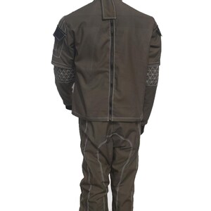 May include: A brown two-piece suit with white stitching. The jacket has a high collar and a zipper down the back. The sleeves have geometric patterns. The pants have white stitching down the front.