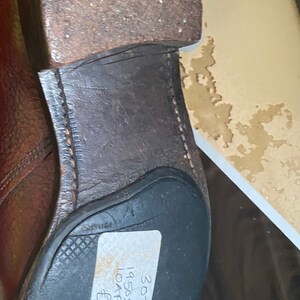 May include: A brown leather loafer with a black rubber sole. The shoe has a price tag attached to it that reads "30-TR 1950s Antelope Loafers &pound;8.95".