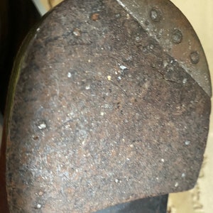 May include: Close-up of a worn leather shoe sole with a metal heel plate. The sole is brown and has a rough texture. The heel plate is silver and has a few small holes.