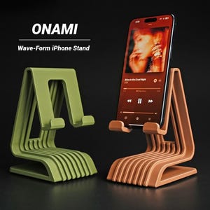 Puede incluir: Dos soportes para iPhone con forma de onda, uno en verde oliva y otro en color terracota, se muestran sobre un fondo oscuro. Los soportes tienen un diseño único de listones y están etiquetados como "ONAMI Wave-Form iPhone Stand."