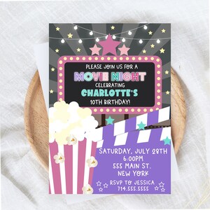 May include: A purple and pink movie night party invitation with a popcorn bucket, a movie clapperboard, and stars. The invitation says "Please join us for a Movie Night celebrating Charlotte's 10th Birthday!"  Saturday, July 28th, 6:00pm, 555 Main St., New York. RSVP to Jessica 714.555.5555.