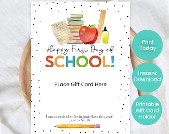May include: A white gift card with black polka dots and the text "Happy First Day of SCHOOL!" in colorful letters. The card features watercolor illustrations of school supplies, including an apple, books, and a pencil. It says "Place Gift Card Here".