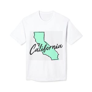 May include: White t-shirt featuring a mint green outline of the state of California. The word "California" is written in a cursive font across the state's outline. The shirt is a classic crew neck style.