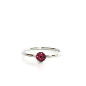 May include: A simple silver band ring with a single, small, round, red gemstone.