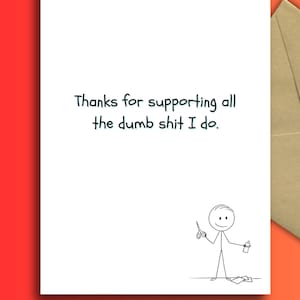 May include: A white greeting card with the text "Thanks for supporting all the dumb shit I do." features a stick figure holding scissors and a bottle. A brown envelope is partially visible on an orange background.