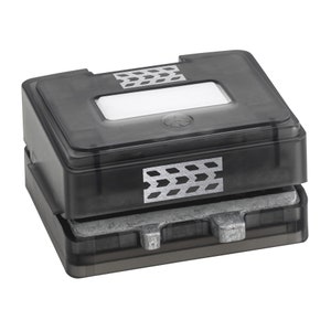 Puede incluir: Un troquel de manualidades de plástico negro con una parte superior transparente y una base de metal plateado. La parte superior tiene una ventana rectangular y patrones decorativos de flechas plateadas. Para manualidades y álbumes de recortes.