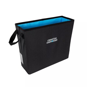 May include: A black fabric storage tote with a rectangular shape and a light blue interior. The tote has a black handle on one side and the words "creative memories" printed in white on the front.