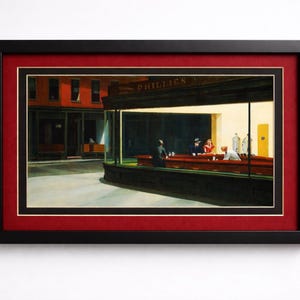 Puede incluir: Impresión enmarcada de la pintura "Nighthawks" de Edward Hopper. La obra representa una escena de restaurante con figuras en la barra, bañadas en luz brillante. El marco es negro con un paspartú rojo.