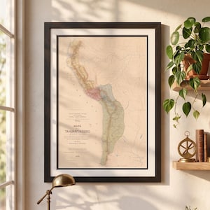 Puede incluir: Mapa antiguo enmarcado de Perú, titulado "Mapa Tahuantinsuyo" en letras negras. El mapa presenta tonos beige, verde y rojo, con un marco negro y un paspartú blanco. El mapa se exhibe en una pared cerca de una ventana, con una lámpara de escritorio y plantas visibles.