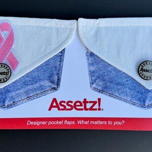 May include: Two denim pocket flaps with white tops. One has a pink ribbon, the other a red "Assetz" patch. Both have a silver button and the "Assetz!" logo. Text reads "Designer pocket flaps. What matters to you?"