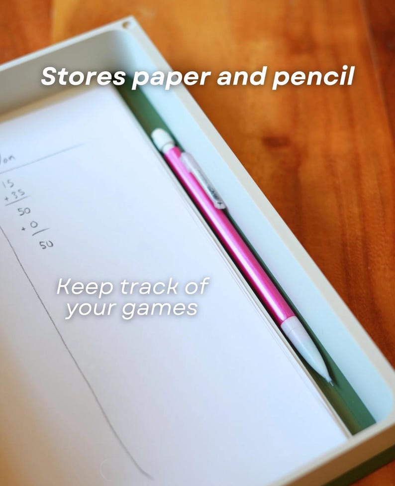 Op de afbeelding: Een wit rechthoekig dienblad met een stapel wit papier met handgeschreven spelscores en een felroze vulpotlood. Op het dienblad staat de tekst Stores paper and pencil en Keep track of your games gedrukt.