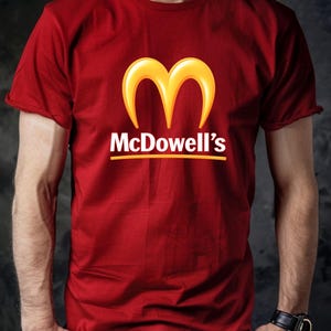 May include: Red t-shirt with the McDowell's logo, featuring a golden arch design and the text "McDowell's" in white. The shirt is short-sleeved and has a casual style.