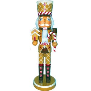 May include: A wooden nutcracker figurine in the shape of a gingerbread man. The figurine is tan with white and red accents, holding a gingerbread house and a candy cane. The nutcracker stands on a round, gold base.