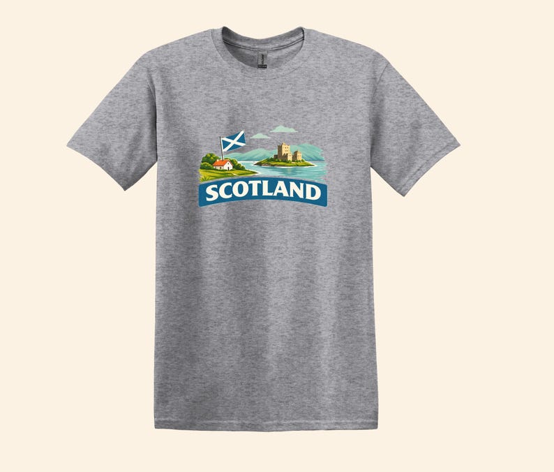 May include: A heather gray t-shirt featuring a graphic of a Scottish landscape with a castle, a flag, and the word "SCOTLAND" in a blue banner. The design is centered on the front of the short-sleeved shirt.