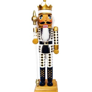 May include: A wooden nutcracker king figure wearing a gold crown and a black and white diamond-patterned uniform. The figure features a white faux fur beard, a black moustache, and holds a tall gold-topped staff while standing on a wooden base.