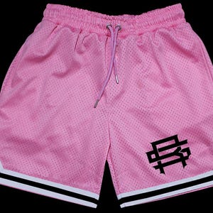 May include: Pale pink mesh shorts with a drawstring waist and a black logo on the left leg. The shorts feature white and black stripes along the sides. The shorts are made of a breathable mesh material.
