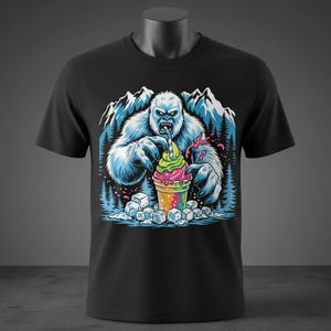 May include: Black t-shirt featuring a colorful graphic of a yeti enjoying a rainbow-colored ice cream treat. The design includes mountains, trees, and ice cubes, creating a fun, whimsical scene. The yeti is depicted with blue fur.