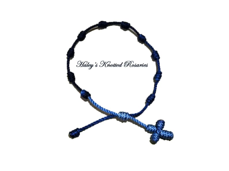 May include: A blue and black knotted rosary bracelet with a blue cross charm. "Haley's Knotted Rosaries" is written in white text on a white background.