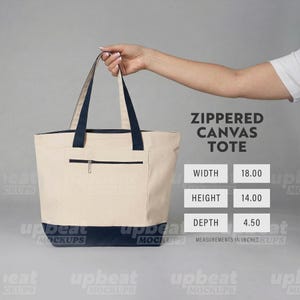 Puede incluir: Bolso tote de lona beige con detalles azul marino. El bolso tiene un bolsillo con cremallera en la parte delantera y asas azul marino. El bolso mide 45,72 cm de ancho, 35,56 cm de alto y 11,43 cm de profundidad.