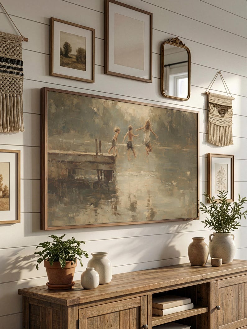 Puede incluir: Una gran pintura enmarcada representa a ni&ntilde;os saltando al agua desde un muelle de madera. La obra de arte est&aacute; rodeada de im&aacute;genes enmarcadas m&aacute;s peque&ntilde;as, un espejo y tapices decorativos. Debajo hay un mueble de madera con plantas y jarrones.