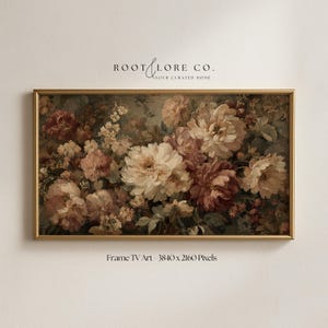 May include: A framed floral print featuring a lush arrangement of peonies and other flowers in shades of cream, pink, and burgundy. The artwork is set against a muted background with a gold-colored frame. The text "ROOT & LORE CO. YOUR CURATED HOME" is at the top.