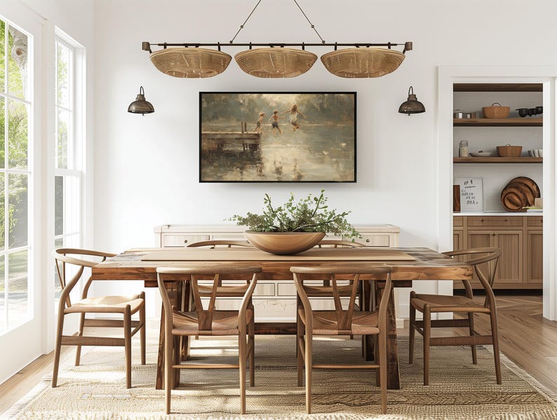 Puede incluir: Un comedor con una mesa de madera y sillas, una alfombra tejida y una pintura enmarcada. Encima de la mesa cuelga una l&aacute;mpara con tres pantallas en forma de cestas tejidas. La habitaci&oacute;n tiene paredes blancas y una paleta de colores neutros.