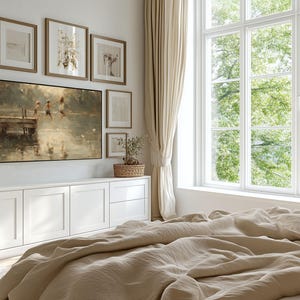 Puede incluir: Una habitaci&oacute;n con una gran ventana y cortinas beige. Una pintura de ni&ntilde;os saltando al agua cuelga sobre un mueble blanco. Varias obras de arte enmarcadas est&aacute;n dispuestas en la pared. Una cama con ropa de cama beige est&aacute; en primer plano.