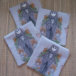 May include: Four square coasters with a light gray background. Each coaster features a black and white illustration of a skeleton figure in a coffin, with the words "Long Time Running" on a green banner. Orange flames and jack-o'-lanterns surround the figure.