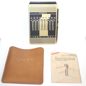 May include: A vintage Tower adding and subtracting machine with a gold and black face, numbers, and the word "ADDITION." Includes a brown leather case and instruction sheet. A classic office supply.