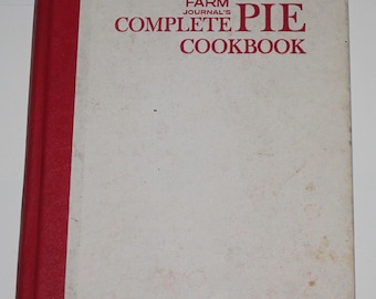Puede incluir: Un libro de cocina blanco con una encuadernación roja y el título "Farm Journal's Complete Pie Cookbook" en letras rojas.
