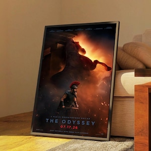Puede incluir: Un póster de película enmarcado titulado The Odyssey, que muestra a un guerrero con casco de cresta roja ante la silueta oscura y ardiente de un caballo. El texto dice A Film by Christopher Nolan, The Odyssey, 07.17.26 y Shot Entirely with IMAX Film Cameras.