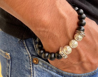 May include: A black beaded bracelet with silver metal accents. The bracelet has a textured, round bead design.