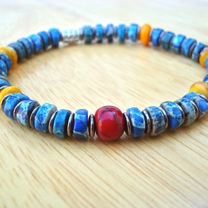 May include: A blue, yellow, and red beaded bracelet with a silver clasp. The beads are made of a marbled stone.