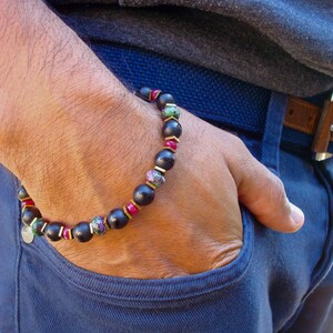 May include: A black beaded bracelet with gold accents and green and red gemstone beads.