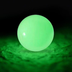 May include: A glowing, spherical object emits a bright green light against a dark background. The sphere appears to be floating above a textured, green surface. The overall effect is a vibrant, luminous display.