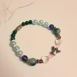 Puede incluir: Una pulsera de cuentas coloridas con cuentas verdes, azules, moradas y transparentes. Incluye un dije de &aacute;ngel plateado y cuentas en forma de coraz&oacute;n. La pulsera est&aacute; dise&ntilde;ada para el uso diario.