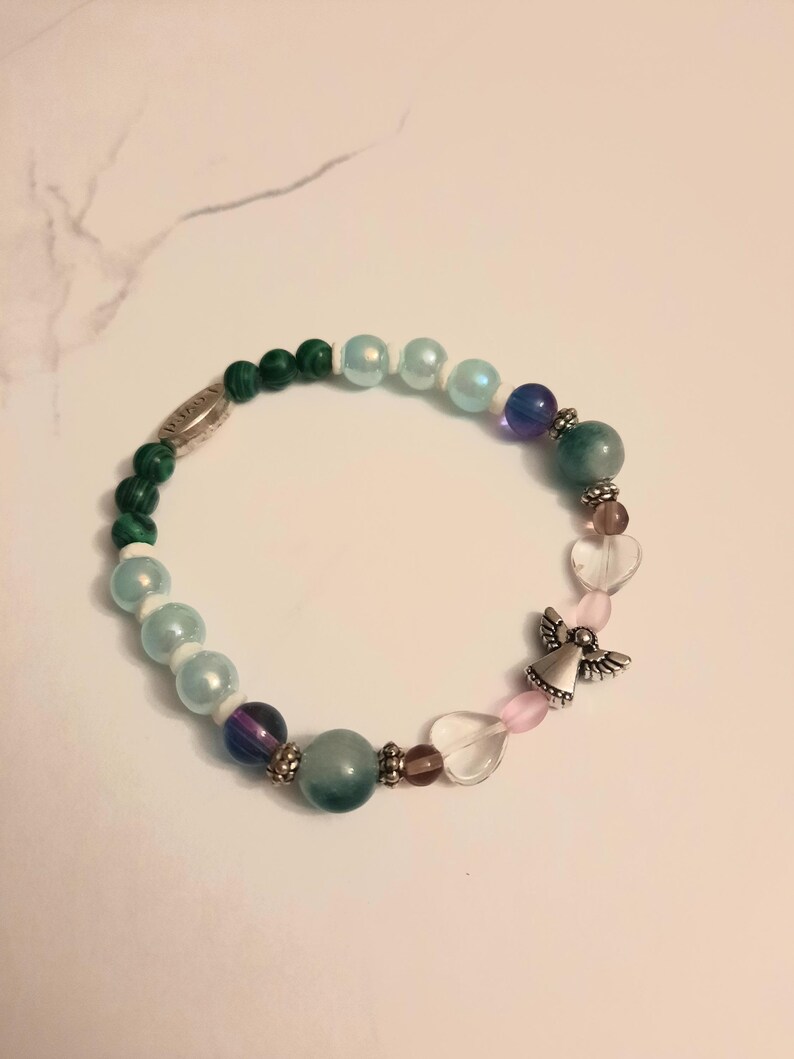 Puede incluir: Una pulsera de cuentas coloridas con cuentas verdes, azules, moradas y transparentes. Incluye un dije de &aacute;ngel plateado y cuentas en forma de coraz&oacute;n. La pulsera est&aacute; dise&ntilde;ada para el uso diario.