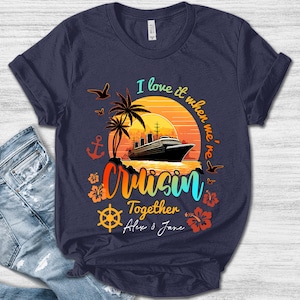May include: Navy blue t-shirt with a colorful graphic of a cruise ship at sunset. The design includes palm trees, birds, and the words "I love it when we're Cruisin' Together". The names Alex & Jane are also included.
