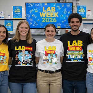 Puede incluir: Cinco personas con camisetas con el texto "LAB WEEK 2026" y gr&aacute;ficos de dibujos animados. Las camisetas son amarillas, negras y blancas. Una pantalla en el fondo tambi&eacute;n muestra "LAB WEEK 2026".