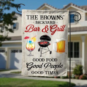 May include: A backyard garden flag with the text "THE BROWNS' BACKYARD Bar & Grill." The flag features illustrations of a cocktail, a grill with steaks, and a beer mug. The words "GOOD FOOD, GOOD PEOPLE, GOOD TIMES" are also printed on the flag.