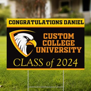 May include: A black and yellow graduation yard sign with the text "CONGRATULATIONS DANIEL" at the top. The sign features a college logo with an eagle and the words "CUSTOM COLLEGE UNIVERSITY" and "CLASS of 2024".